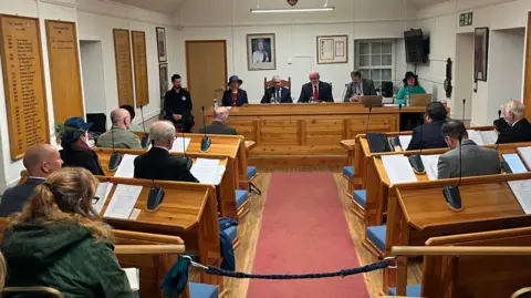 Chief Pleas - A courtroom setting with a number of people sitting behind desks. 