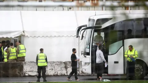 Reuters People board a bus at the migrant processing centre in Manston