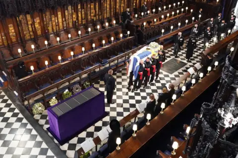 PA Media Queen Elizabeth II (L) watches as pallbearers carry the coffin of Britain's Prince Philip, Duke of Edinburgh during his funeral inside St George's Chapel in Windsor Castle in Windsor, west of London, on April 17, 2021.