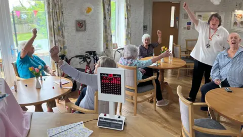 Residents cheer with the electronic bingo number generator in the forefront of the picture