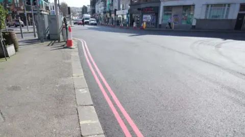 A road with two red lines painted along the side of it.