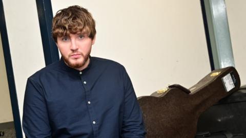 James Arthur with guitar cases behind him