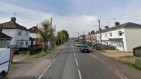 A Google street view perspective of Norwood Road in March. There are two rows of detached and terraced houses either side of the road and a few cars parked in driveways and on the road. 