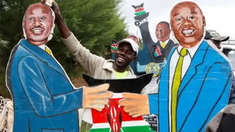 Getty Images vendor holds an artistic expression representing Kenya"s President-elect William Ruto and his deputy Rigathi Gachagua outside his official residence in Karen district of Nairobi, Kenya, August 17, 2022.