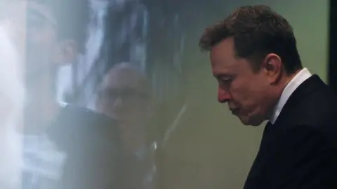 Elon Musk prepares to walk through security at the federal courthouse in Oakland, California on a day in late April