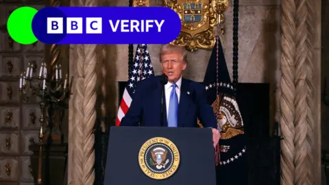 US President Donald Trump speaking at a podium, a BBC Verify logo is added