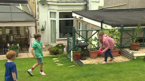 Seren, Deian and Owain Iago playing football in their garden