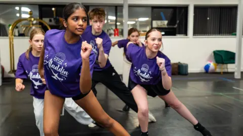 Tom Soper A group of young performers go through their dance routine ahead of appearing in Aladdin at the Theatre Royal in Bury St Edmunds. They are all wearing purple T-shirts with the pantomime's logo on them