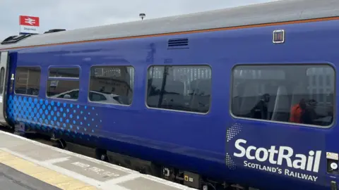 A ScotRail coach at Inverness Station. The coach's livery is blue and white.