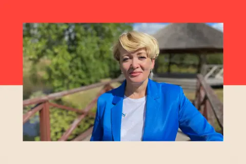 Anastasia Shevchenko smiling and wearing a blue jacket in a rural scene