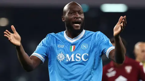 Romelu Lukaku in Napoli's light blue shirt, with raised arms held out in front of him