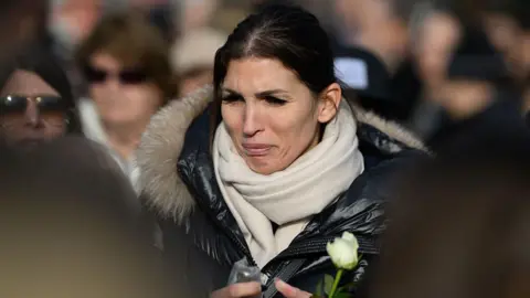 AFP via Getty Images A woman cries holding a white flower