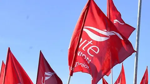 Union Red large flags flying in the air with the words UNITE UNION in white printed on them