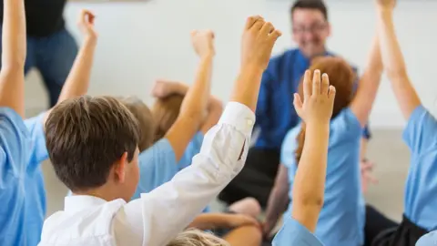 School children raising their hands in a classroom