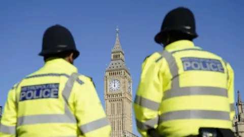 Andrew Matthews/PA Wire Two police officers wearing hi-vis jackets reading 'Metropolitan Police' are in the foreground, looking ahead towards the Elizabeth Tower.