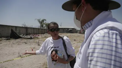 Reuters A woman wearing a T-shirt with the image of a missing relative stands behind a crime-scene tape at the Izaguirre Ranch and gestures towards the sand behind here while speaking to a man.