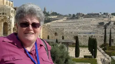 Family Photo A holiday picture of the victim, Davinia Graham, shows her wearing sunglasses and smiling at the camera, in front of a number of stone buildings stretching into the background.