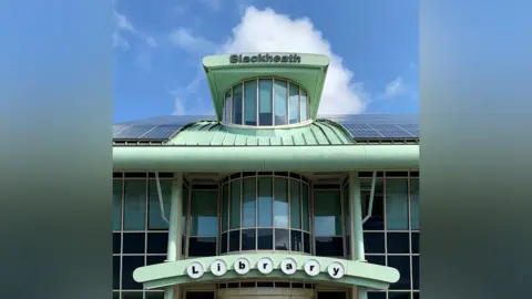 Tom Hicks Blackheath library is captured which is mint green and has the words Blackheath at the top of the building with each letter for the word library in circles above the entrance.
