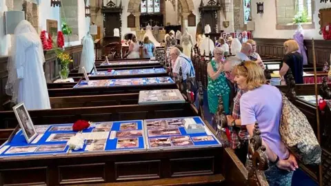 Carol Atkinson People read snippets of memories held at an exhibition inside St Andrew's Church. There are photographs laid out and weddings clothes held up on mannequins.
