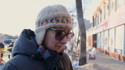 A woman talks to the BBC wearing sunglasses.