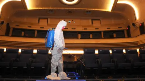 Getty Images A worker disinfects a cinema hall in Patiala, India