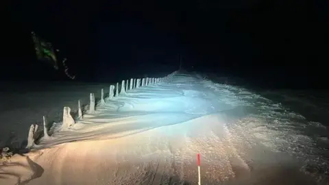 Highland Council drifting snow on a country road, photographed at night