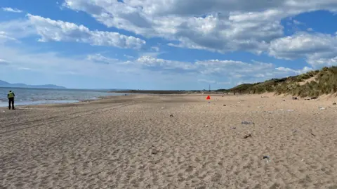 A general view of Irvine Beach with a police officer and police tape on the scene.