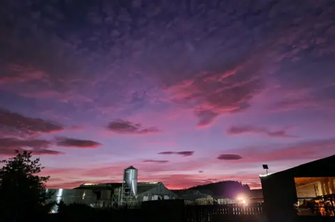 farm outlook/BBC Weather Watchers Pink clouds above farm buildings.