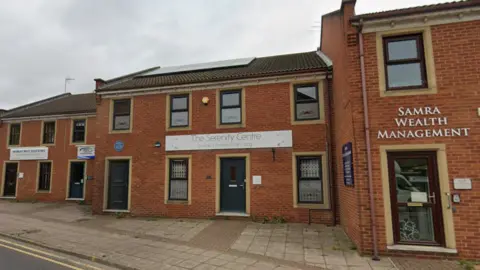Google A modern brick two storey building - with a white sign reading The Serenity Centre. 