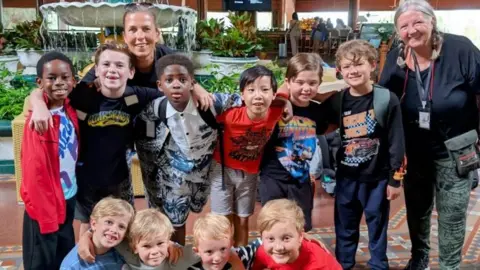 Contributed A group of young boys smile at the camera in a group with their two female chaperones. 