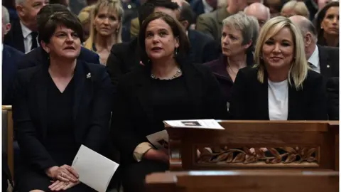 Getty Images DUP leader, Arlene Foster, seated alongside leader of Sinn Féin, Mary Lou McDonald, and Sinn Féin Vice-President, Michelle O'Neill in St. Anne's Cathedral