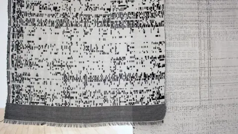 British Textile Biennial Picture of two tapestries being shown in this year's Biennial. They've woven in white, grey and black threads and hang from the wall in the museum. 