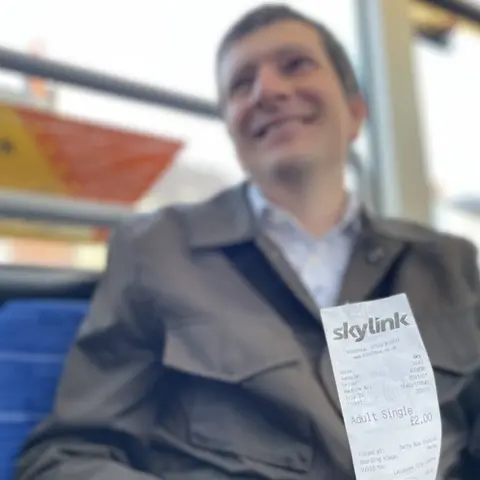 Andrew Cowell holding his £2 bus ticket from Derby to Leicester