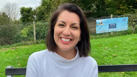 A woman with with dark shoulder-length hair looking and smiling at the camera