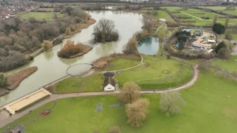An aerial view of Wicksteed park with paths and a big lake.