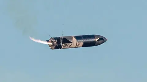 SpaceX Starship performing a "belly flop" maneuver while falling back to Earth before firing its engines to flip it into a vertical position.