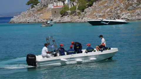 PA Media Emergency workers leave Agia Marina in Symi, Greece, where the body of TV doctor and columnist Michael Mosley was discovered.