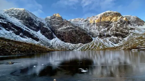 Paul Weir Snowy mountains surrounding icy water.