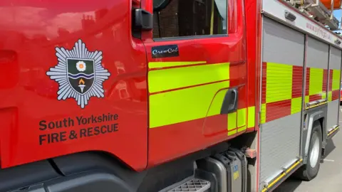 A red and yellow fire engine with South Yorkshire Fire & Rescue written on the front