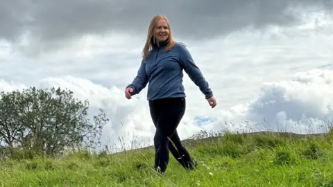 A woman walks through a field