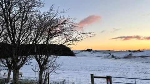 BBC Weather Watchers/Olga Field covered in snow and sunrise behind over the hills