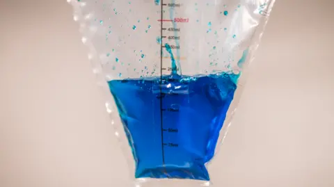 Gates Archive/Brian Otieno A plastic see-through drape with blue fluid inside against a beige background