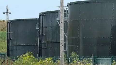 Three large grey round waste containers at the landfill site