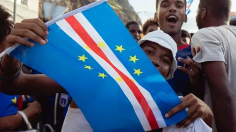 QUEILA FERNANDES / AFP / GETTY IMAGES Young men celebrate on the streets after the match and wave the national flag.
