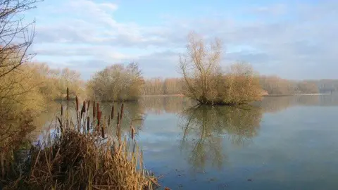 Geograph/Andrew Smith A wide lake surrounded by autumnal foliage on a day with clear blue skies