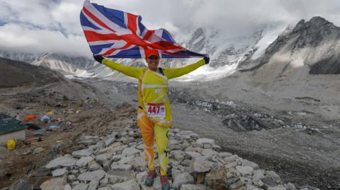 Sally Orange holding the British flag near Mount Everest