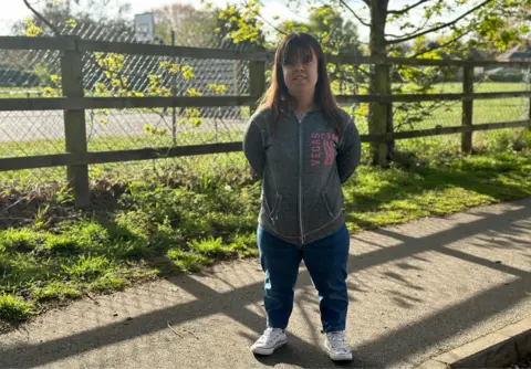 Zoe Newson standing on a footpath outside East Bergholt Primary School