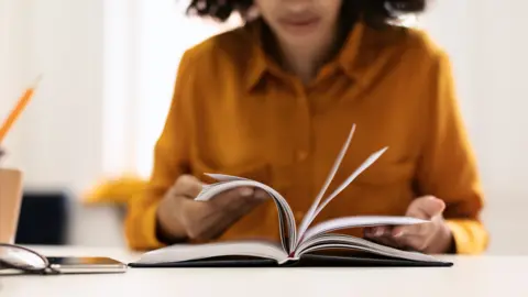 Getty Images A teacher reads through a book