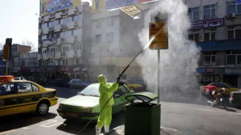 EPA A municipal employee disinfects a road sign in Tehran, Iran. Photo: 5 Mach 2020
