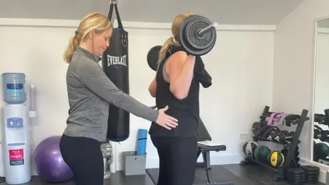 Kim Ovel Kim Ovel with one of her personal training clients, assisting her with a squat